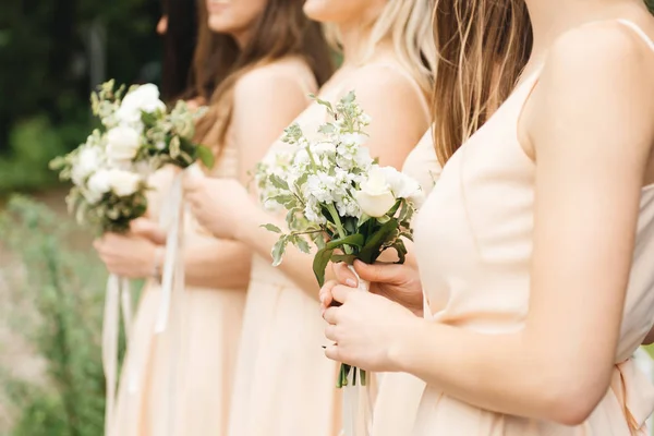 Härliga brudtärnor i ljusa klänningar med vackra blommor — Stockfoto