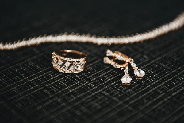 Bröllopssmycken för kvinnor (örhängen, ringar och armband) på ett mörkt — Stockfoto