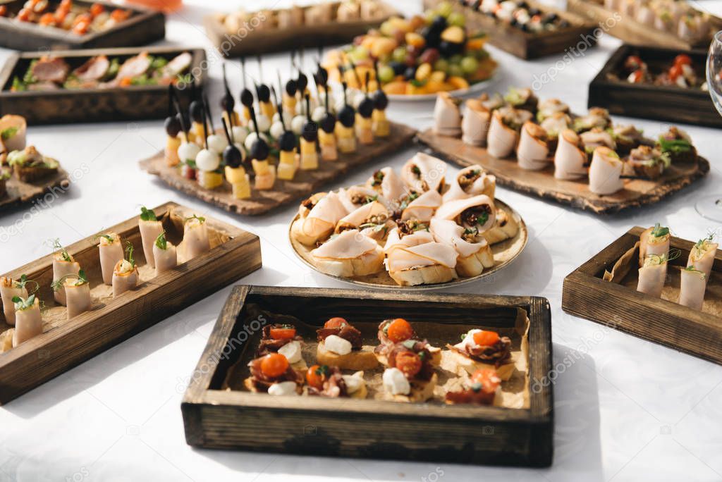 the buffet at the reception. Assortment of canapes on wooden boa