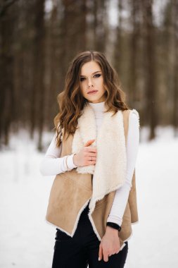 Karlı bir ormanın arka planında şık bir genç kızın portresi.