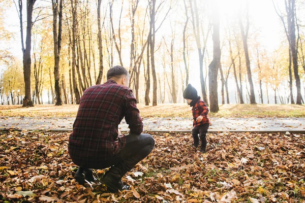 Young dad plays with his son in the autumn Park