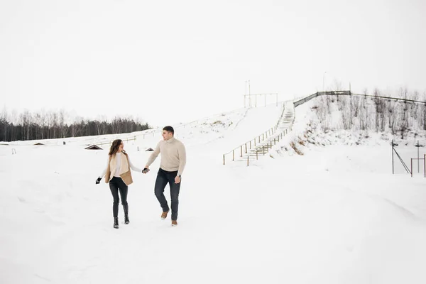 Winter love story on ice. Stylish lovers boy and girl on a snowy background . Romance
