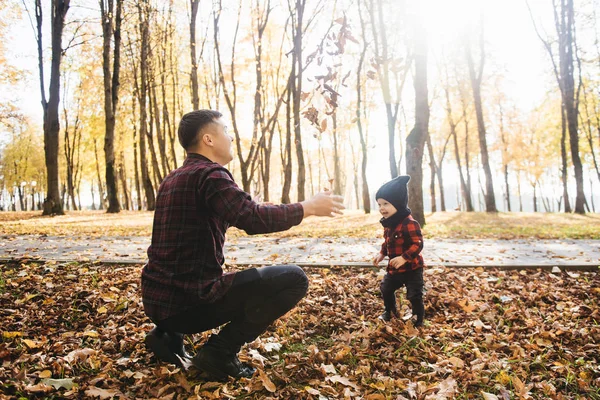 Young dad plays with his son in the autumn Park