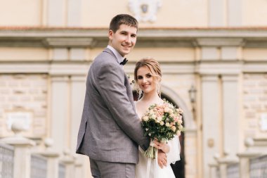 Eski bir binanın arka planında ve kaldırım taşlarında, Avrupa düğününde birbirine aşık güzel, zarif bir çift.