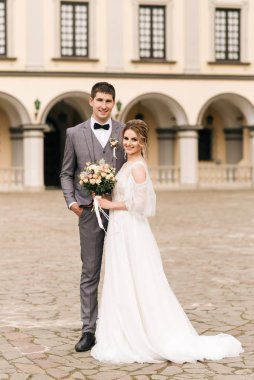 Eski bir binanın arka planında ve kaldırım taşlarında, Avrupa düğününde birbirine aşık güzel, zarif bir çift.