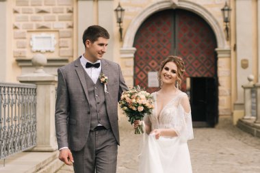 Eski bir binanın arka planında ve kaldırım taşlarında, Avrupa düğününde birbirine aşık güzel, zarif bir çift.