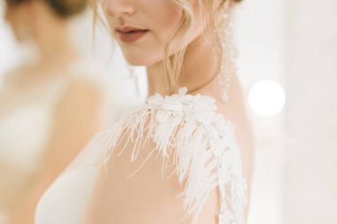 Parlak bir odada romantik bir ortamda genç ve güzel bir gelinin portresi. Gelinlik detaylarının yakın plan çekimi