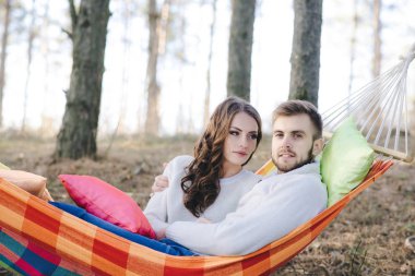 Birbirine aşık çiftler, hamakta oturan kız ve erkek ormanda eğleniyor, seyahat aşkı konsepti.
