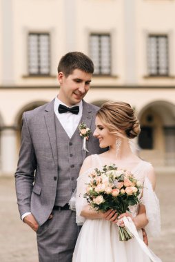 Eski bir binanın arka planında ve kaldırım taşlarında, Avrupa düğününde birbirine aşık güzel, zarif bir çift.