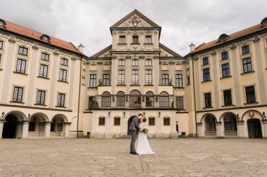 Eski bir binanın arka planında ve kaldırım taşlarında, Avrupa düğününde birbirine aşık güzel, zarif bir çift.