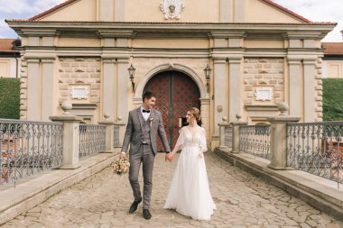 Eski bir binanın arka planında ve kaldırım taşlarında, Avrupa düğününde birbirine aşık güzel, zarif bir çift.