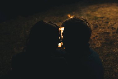 Aşık genç bir çift, ormanda bir çadırın önünde eski bir çelenkle kamp kuruyor. Çok gürültülü bir fotoğraf, seçici bir odak noktası var.