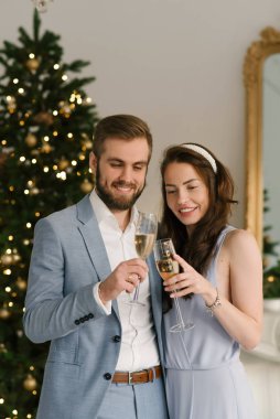 Çekici ve sevecen bir adam ve kız evdeki Noel ağacının arka planında şampanya kadehleriyle, Noel aşk hikayesi konsepti