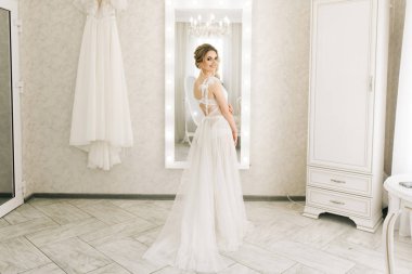 Parlak bir odada romantik bir ortamda genç ve güzel bir gelinin portresi. Gecelikli, düğün saçlı ve makyajlı gelin.