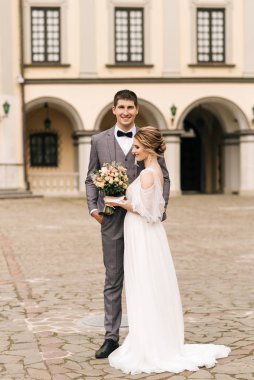 Eski bir binanın arka planında ve kaldırım taşlarında, Avrupa düğününde birbirine aşık güzel, zarif bir çift.