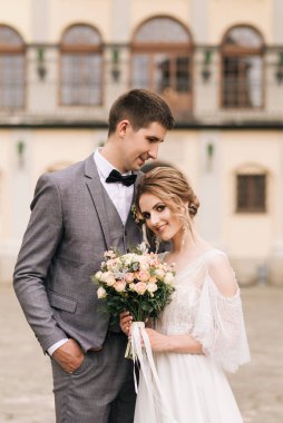 Eski bir binanın arka planında ve kaldırım taşlarında, Avrupa düğününde birbirine aşık güzel, zarif bir çift.