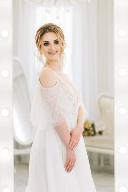 Parlak bir odada romantik bir ortamda genç ve güzel bir gelinin portresi. Düğün makyajı ve saç stili yakın plan.