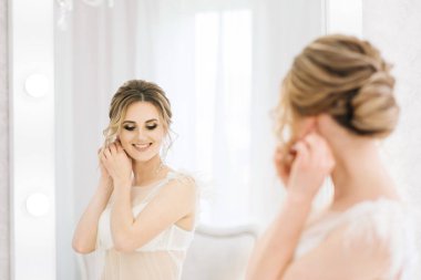 Parlak bir odada romantik bir ortamda genç ve güzel bir gelinin portresi. Gelin mücevher takıyor.