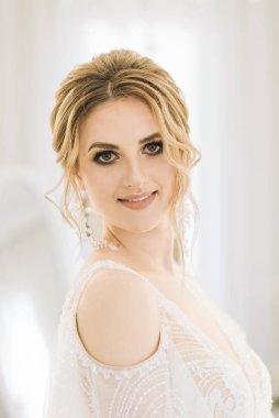 Parlak bir odada romantik bir ortamda genç ve güzel bir gelinin portresi. Düğün makyajı ve saç stili yakın plan.