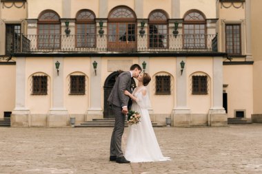 Eski bir binanın arka planında ve kaldırım taşlarında, Avrupa düğününde birbirine aşık güzel, zarif bir çift.