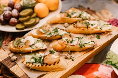 Ahşap tahtada servis edilen jambonlu ve sebzeli lezzetli sandviçler.