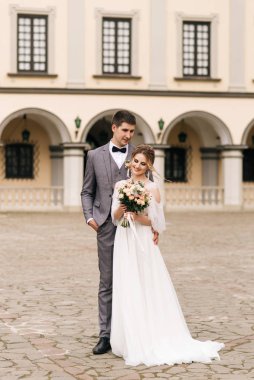 Eski bir binanın arka planında ve kaldırım taşlarında, Avrupa düğününde birbirine aşık güzel, zarif bir çift.