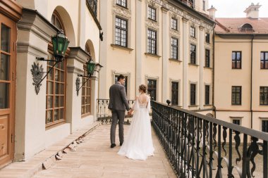 Eski bir binanın arka planında ve kaldırım taşlarında, Avrupa düğününde birbirine aşık güzel, zarif bir çift.