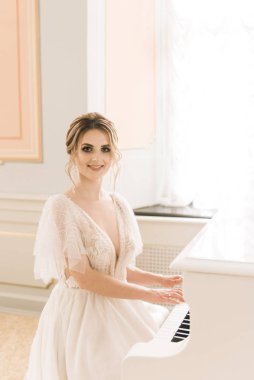 Lüks bir iç mekanda piyanonun yanında güzel bir gelinin portresi.