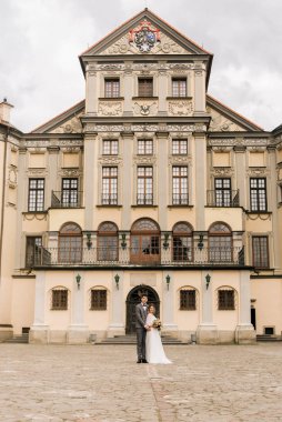 Eski bir binanın arka planında ve kaldırım taşlarında, Avrupa düğününde birbirine aşık güzel, zarif bir çift.