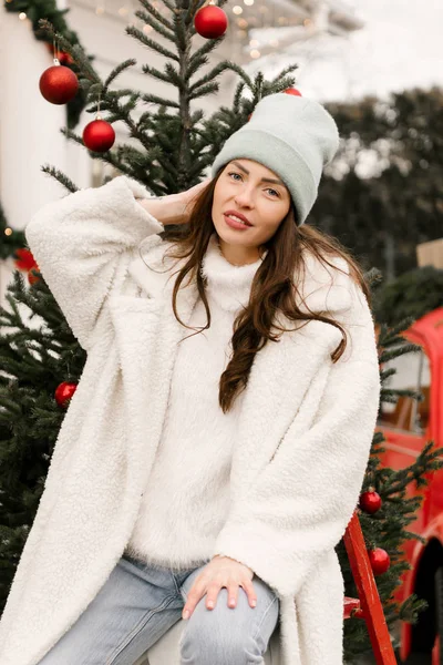 クリスマスツリーの背景に帽子の魅力的なスタイリッシュな女の子の肖像画 — ストック写真