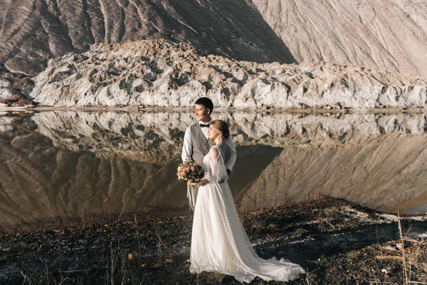 美丽优雅的一对新婚夫妇在美丽的天然盐山和采石场的背景下坠入爱河 — 图库照片