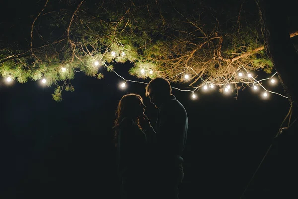 Aşık genç bir çift, ormanda bir çadırın önünde eski bir çelenkle kamp kuruyor. Çok gürültülü bir fotoğraf, seçici bir odak noktası var.