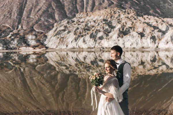 美丽优雅的一对新婚夫妇在美丽的天然盐山和采石场的背景下坠入爱河 — 图库照片