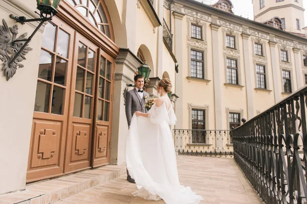 Eski bir binanın arka planında ve kaldırım taşlarında, Avrupa düğününde birbirine aşık güzel, zarif bir çift.