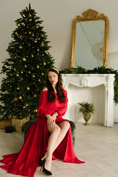 クリスマスツリーの背景に長い赤いドレスを着た魅力的な若い女の子の肖像 — ストック写真