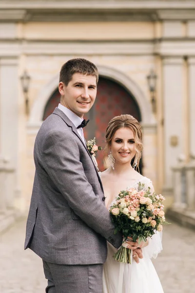 美丽优雅的一对新婚夫妇在一座古老的建筑和铺路石的背景下坠入爱河 欧式婚礼 — 图库照片