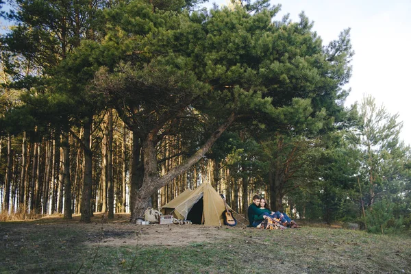 Genç aşıklar kamp yapıyor, kamp ateşinin yanında ormanın içinde çadırın karşısında oturuyorlar. 