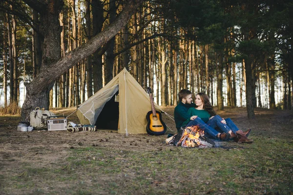 Genç aşıklar kamp yapıyor, kamp ateşinin yanında ormanın içinde çadırın karşısında oturuyorlar. 