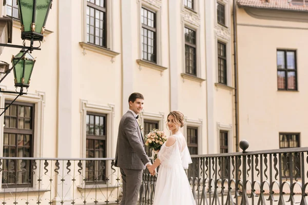 Eski bir binanın arka planında ve kaldırım taşlarında, Avrupa düğününde birbirine aşık güzel, zarif bir çift.