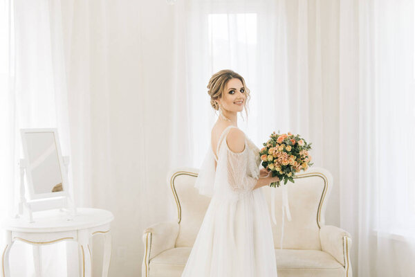 Portrait of a beautiful young bride in a bright room in a romantic atmosphere. Bride with a bouquet of flowers