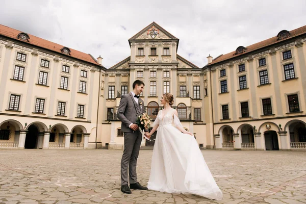 Eski bir binanın arka planında ve kaldırım taşlarında, Avrupa düğününde birbirine aşık güzel, zarif bir çift.