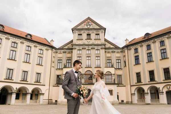 Eski bir binanın arka planında ve kaldırım taşlarında, Avrupa düğününde birbirine aşık güzel, zarif bir çift.