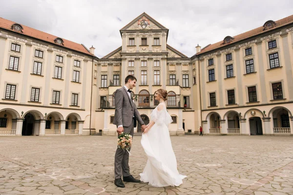 Eski bir binanın arka planında ve kaldırım taşlarında, Avrupa düğününde birbirine aşık güzel, zarif bir çift.