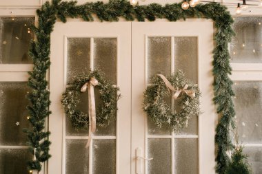 Noel ve yeni yılın dekoru. Çelenklerle süslenmiş güzel bir cephe, seçici bir odak noktası.