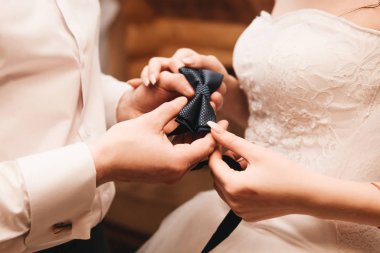 Düğün gününün sabahı. Gelin ve damat papyon tutuyor.