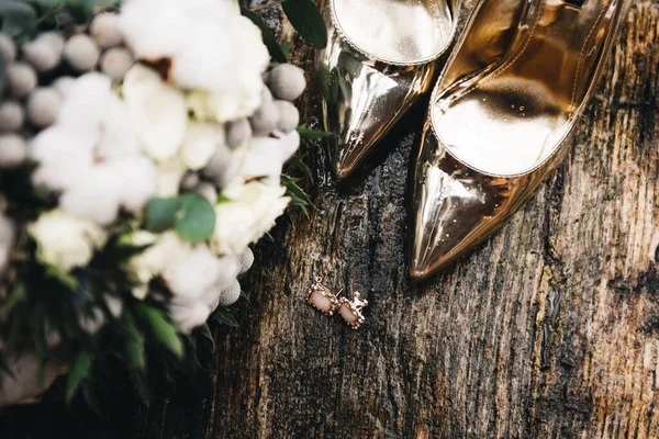 金鞋和新娘的婚礼花束 背景是湿木制的 — 图库照片