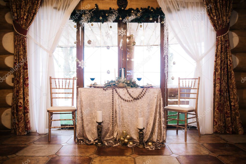 Beautiful serving table with Golden plates decorated with spruce and wine glasses. The concept of Christmas