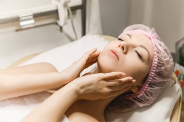 Kozmetik ve estetik cerrahının resepsiyonundaki çekici bir kızın yakın plan portresi, kozmetoloji, kırışıklık giderme, yüz masajı.