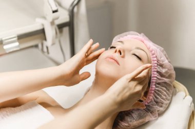 Kozmetik ve estetik cerrahının resepsiyonundaki çekici bir kızın yakın plan portresi, kozmetoloji, kırışıklık giderme, yüz masajı.