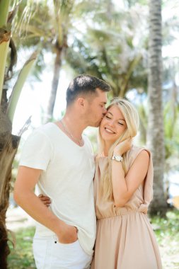 Çekici bir adamın portresi ve doğanın arka planına karşı bir kız. Palmiye ağaçlarının yanında poz veren gezginlerin fotoğrafı.